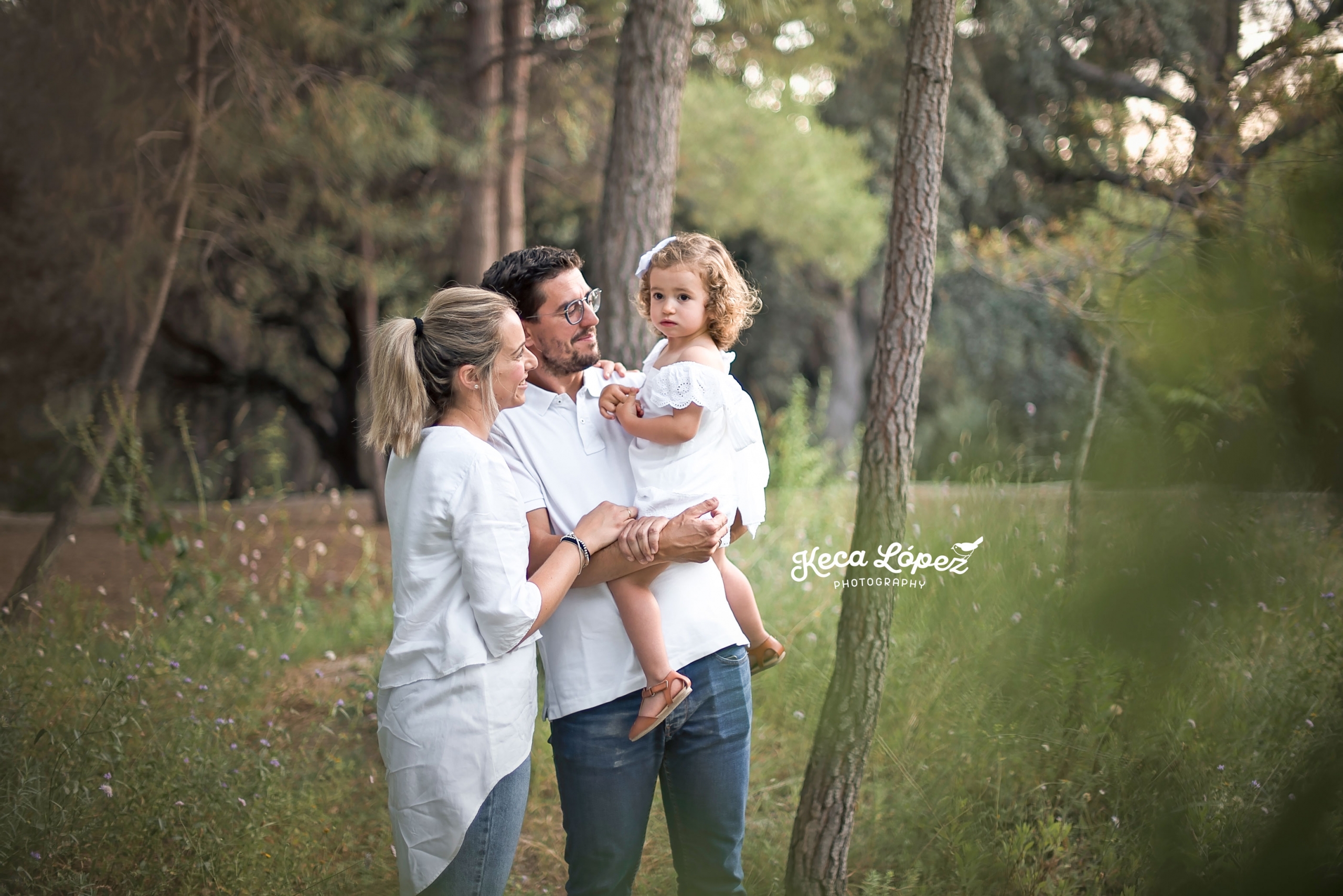 Fotografia de una familia en el bosque. Llevan vestidos blancos y vaqueros