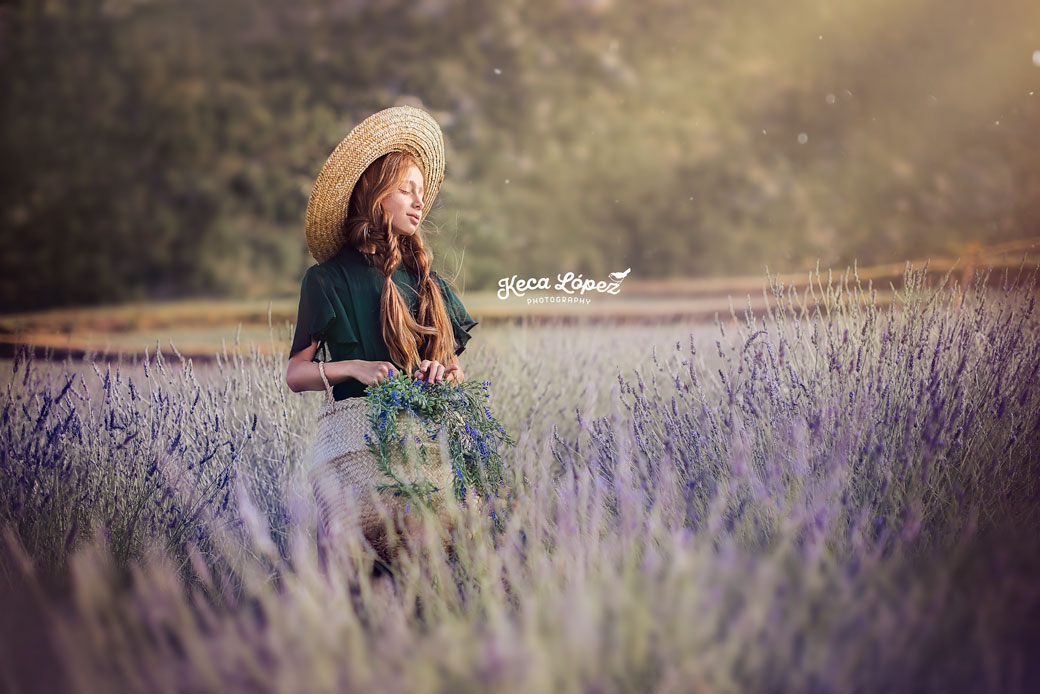 Niña en el campo de lavanda de San Juan en Murcia. Lleva un sombrero de paja y un vestido verde.
