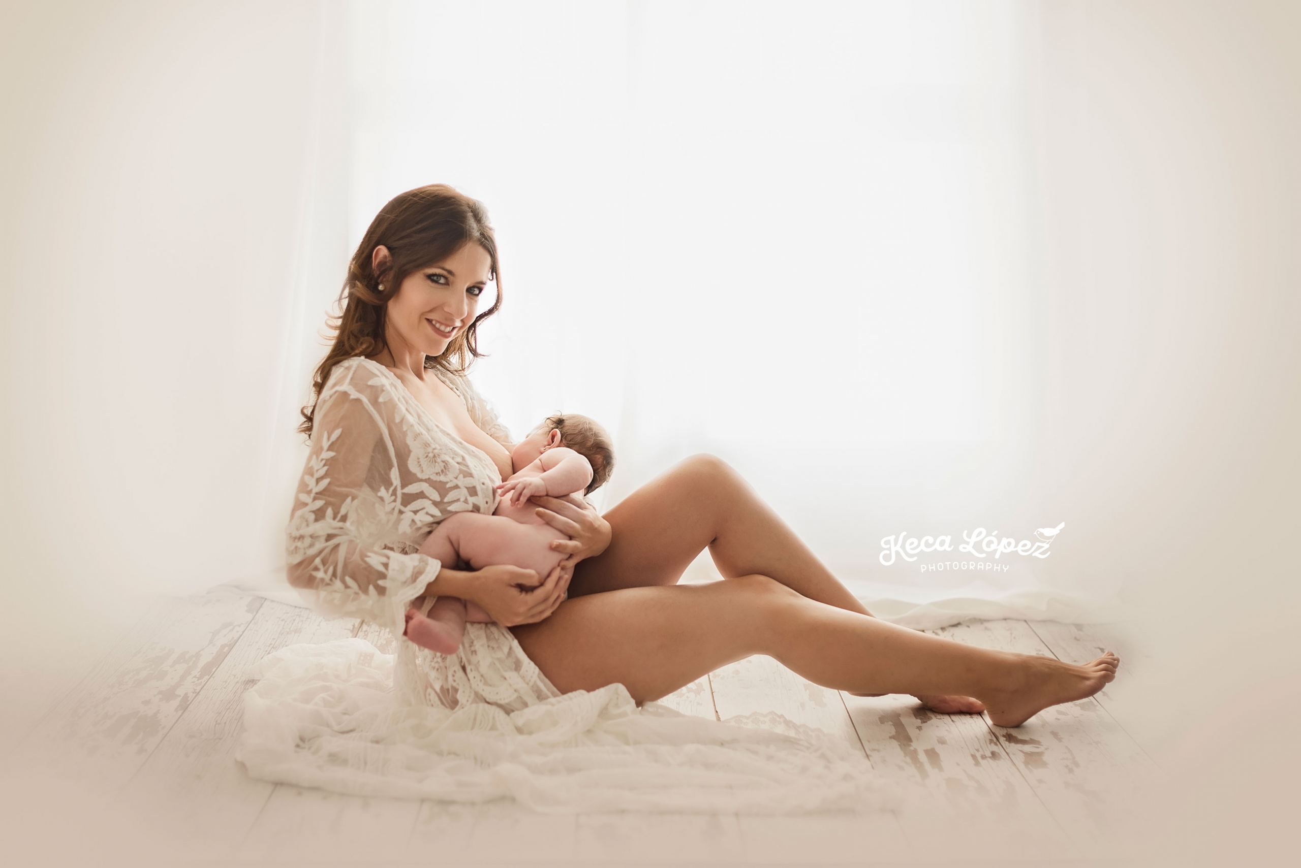 Mujer dando pecho a su bebé con un vestido blanco de encaje